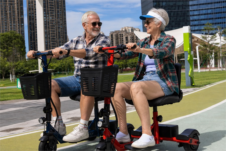  Older adults riding foldable 3-wheel mobility scooters on a paved community path