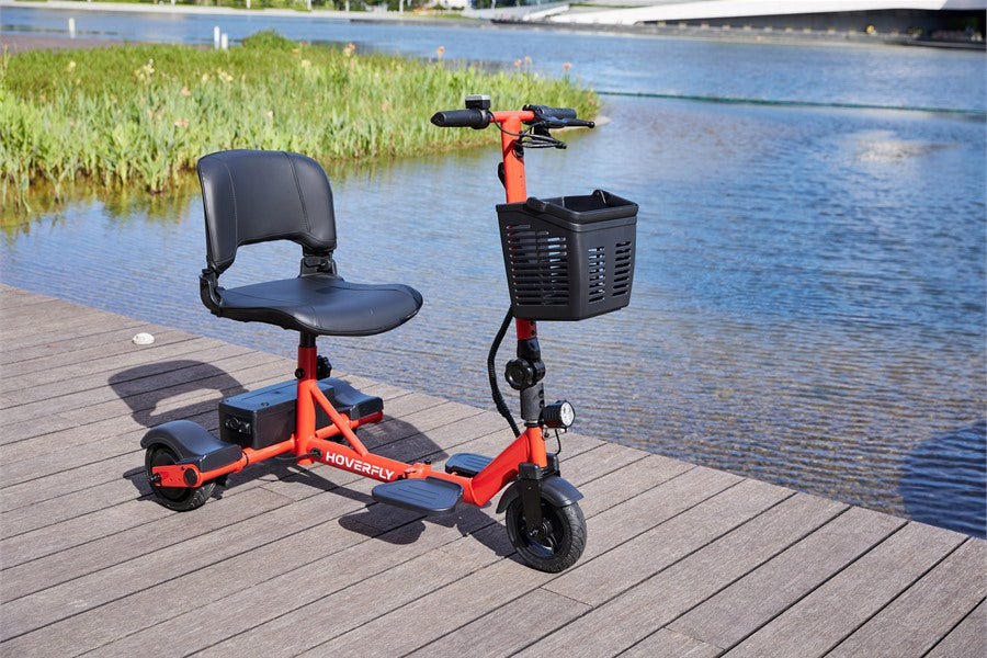 Hoverfly's Blue three-wheel mobility scooter with basket on a park path, highlighting a convenient travel-friendly design for elderly women.