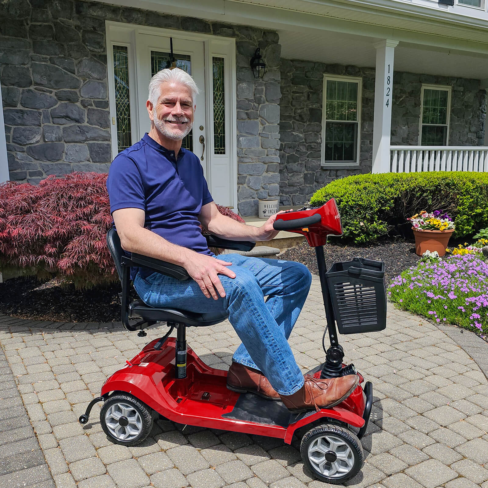 Man sitting on a hoverfly red mobility scooter in front of a house